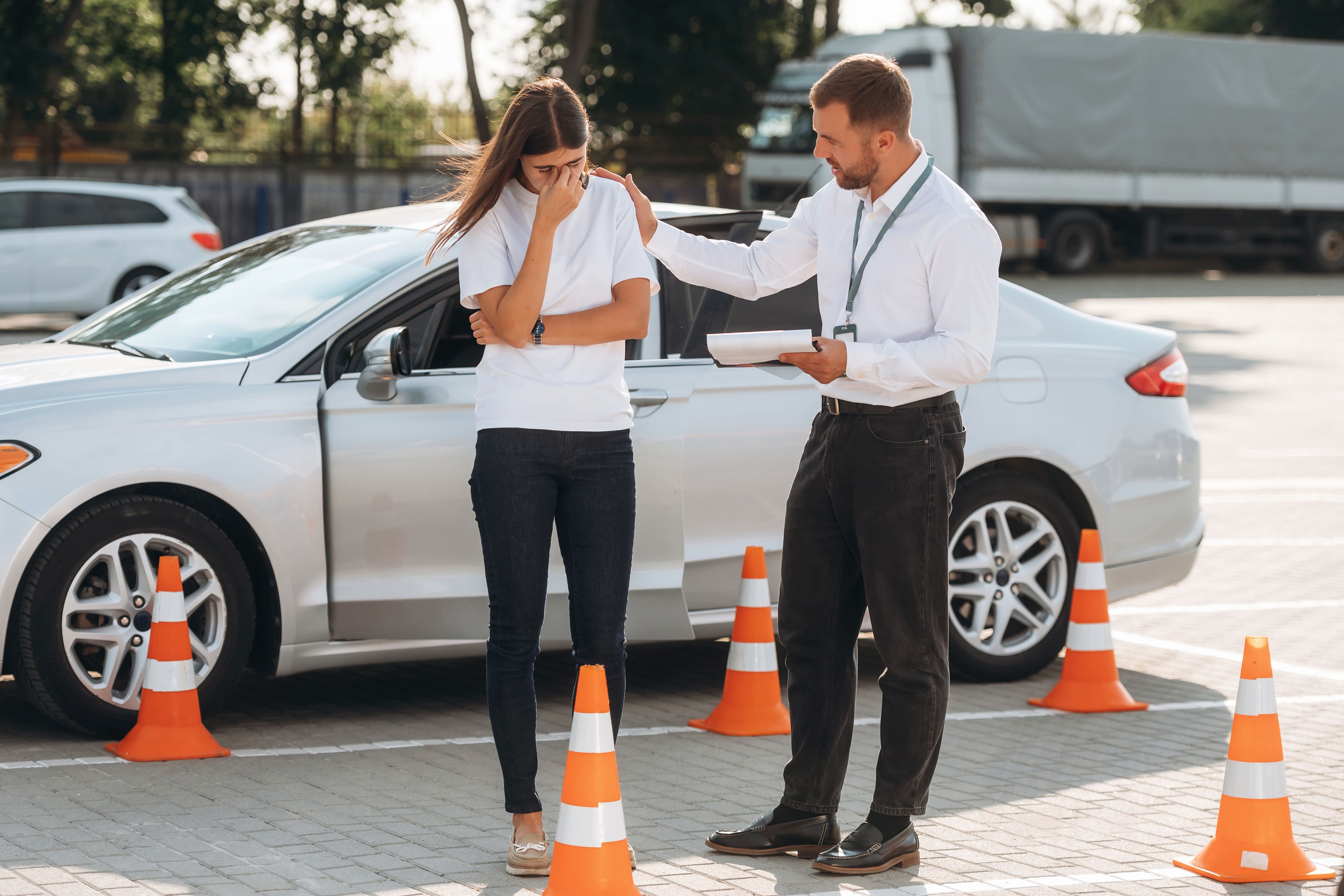 Joven al volante cometiendo errores comunes al aprender a conducir, instructor señalando consejos de seguridad en el interior del coche